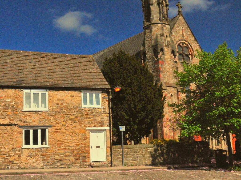 an old brick building with a church with a tower at Newbiggin Cottage in Richmond
