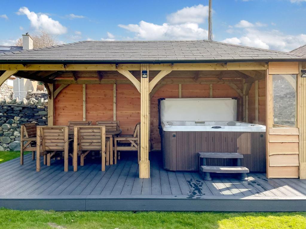 a gazebo with a table and chairs and a hot tub at Yr Hen Weithdy in Llanllechid