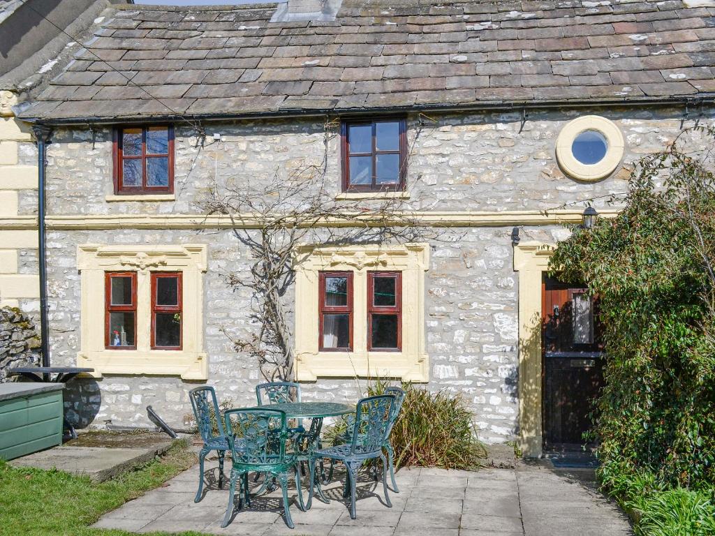 a table and chairs in front of a stone house at Bellypig Cottage in Bellerby
