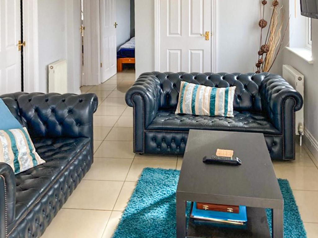 a living room with a black leather couch and a coffee table at Ivy No1 - Uk49251 in Althorne