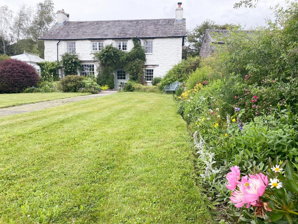 a large white house with a yard with flowers at Thwaite Bridge Houseconiston in Coniston