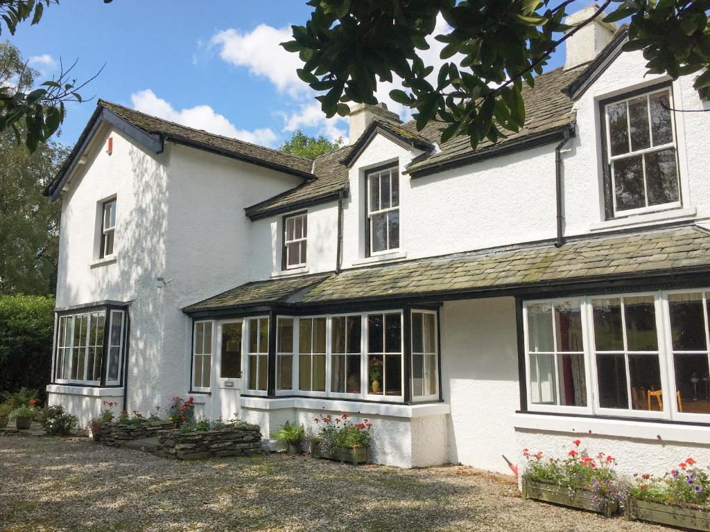 a white house with windows and flowers in the yard at The Vicarage in Lowick Green