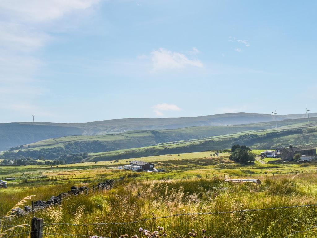 a field of grass with hills in the background at Limestone Cottage in Hebden Bridge