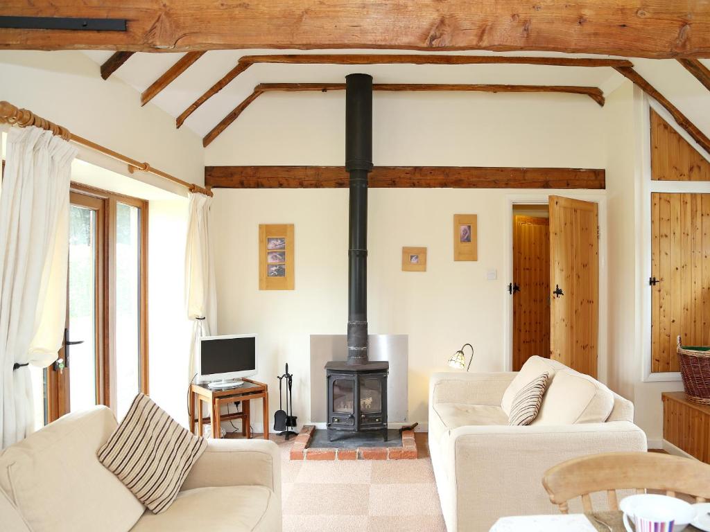 a living room with white furniture and a wood stove at The Dairy At Copper Beeches in Petersfield