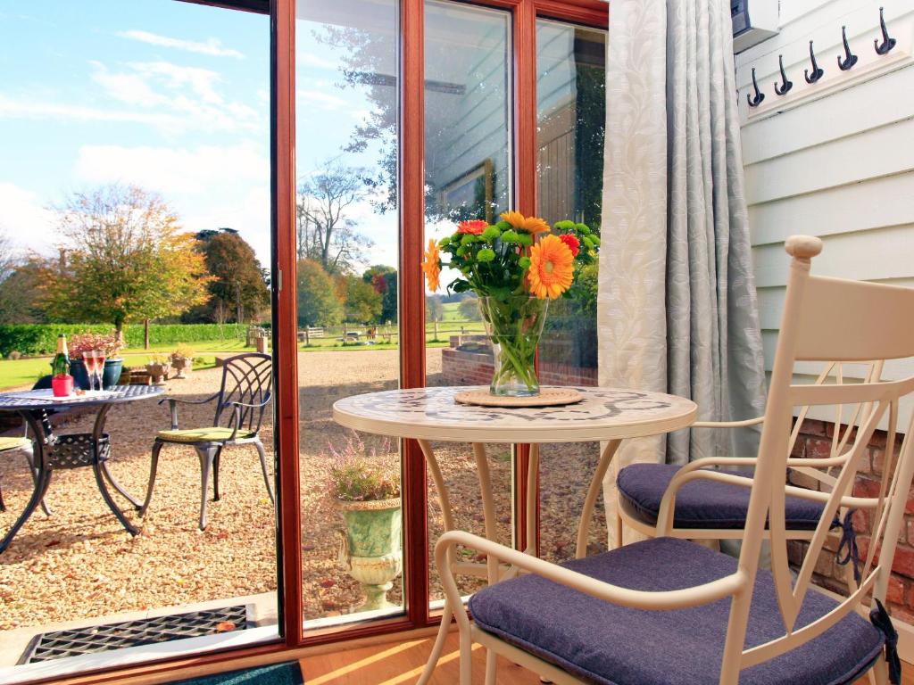 ein Tisch mit einer Blumenvase auf einer Veranda in der Unterkunft Alpaca Cottage in Frampton
