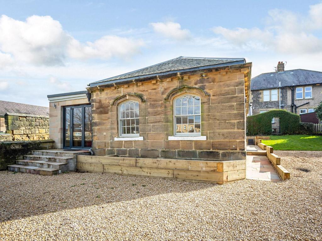 a small brick house with windows on a gravel yard at Glebelands Lodge in Alnwick