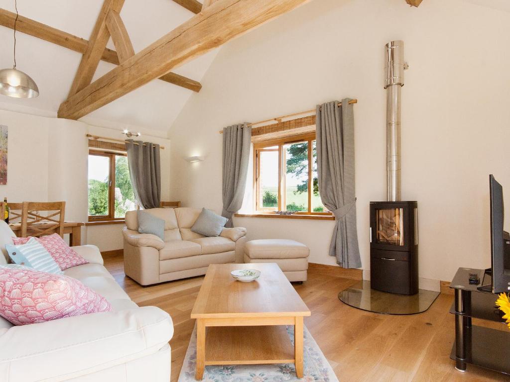 a living room with white furniture and a fireplace at Meadow Barn - Blackdown Farm in Blackawton