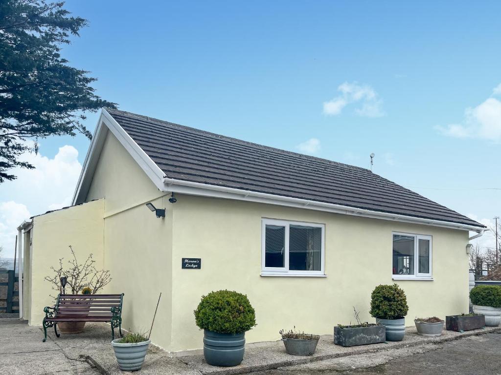 a white house with potted plants in front of it at Heron's Lodge in Llanarthney