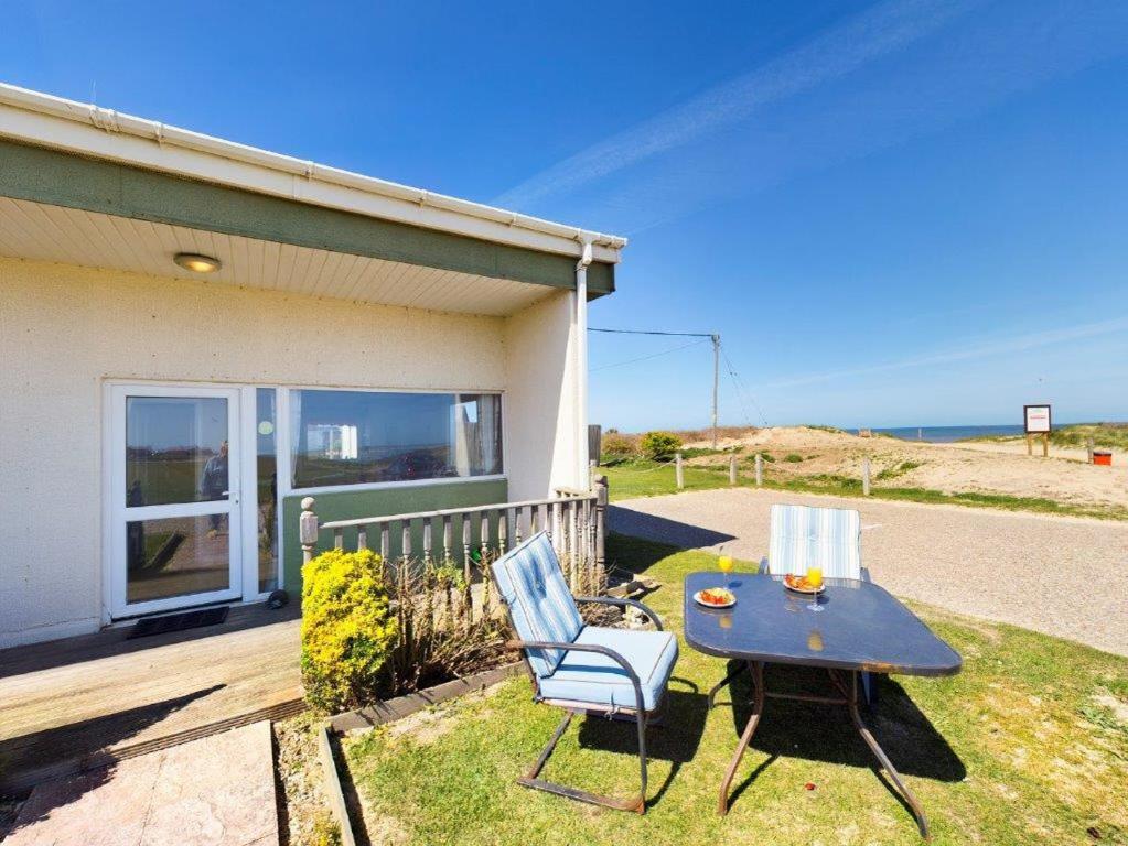 a patio with a table and chairs and the ocean at On The Beach in Bacton