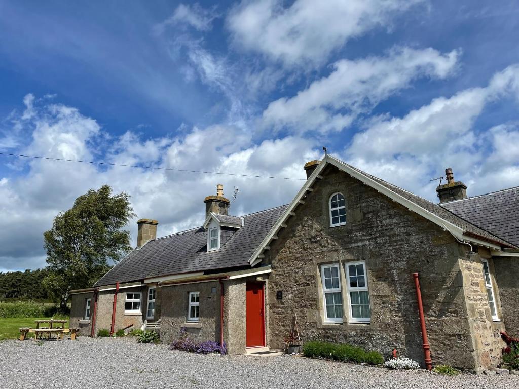 an old stone house with a red door at Birch Cottage - Uk38992 in Dalcross