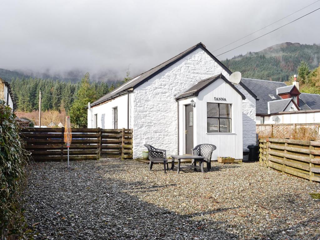 a white building with a bench and a fence at Sanna in Ardentinny