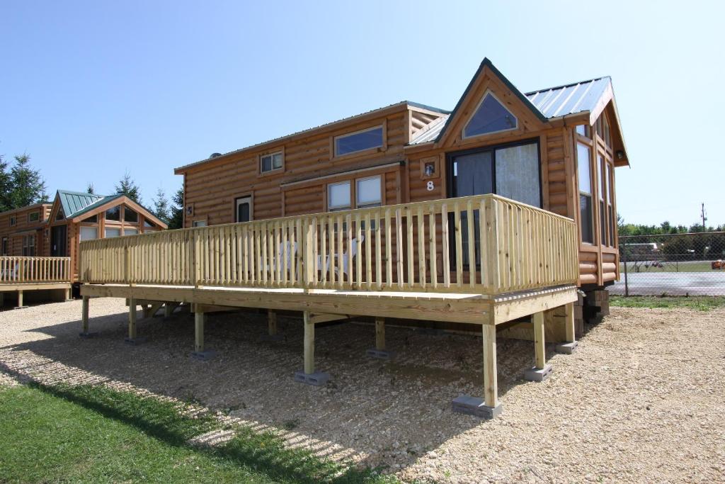 een blokhut met een veranda en een huis bij Lakeland RV Campground Loft Cabin 1 in Edgerton