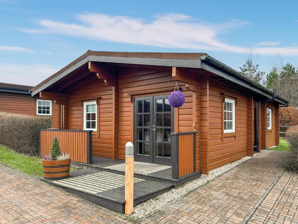 a small wooden cabin with a porch and a purple ball at Lodge 4 - Uk51264 in Glasgow
