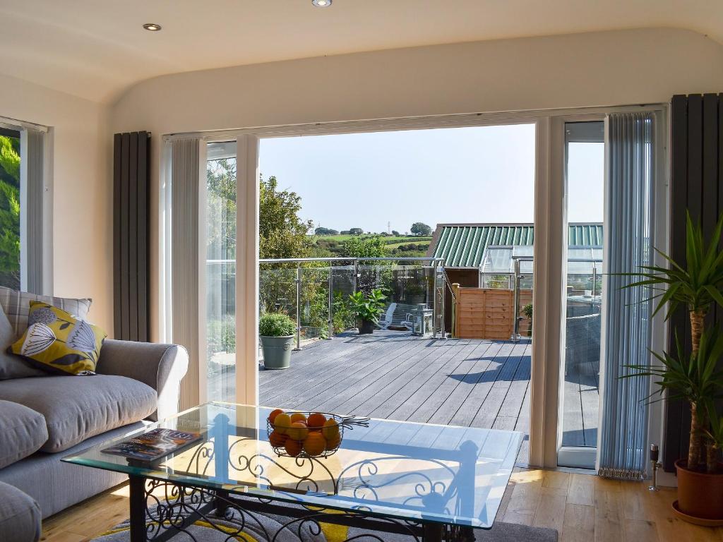 a living room with a glass coffee table and a balcony at Y Bwthyn At Tyddyn Obry in Llanfaelog