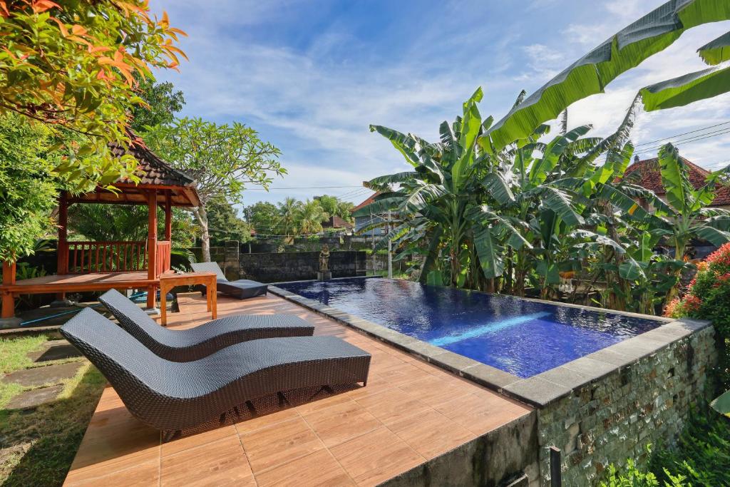 a backyard with a swimming pool and a wooden deck at The Tandjung Cottage in Nusa Penida