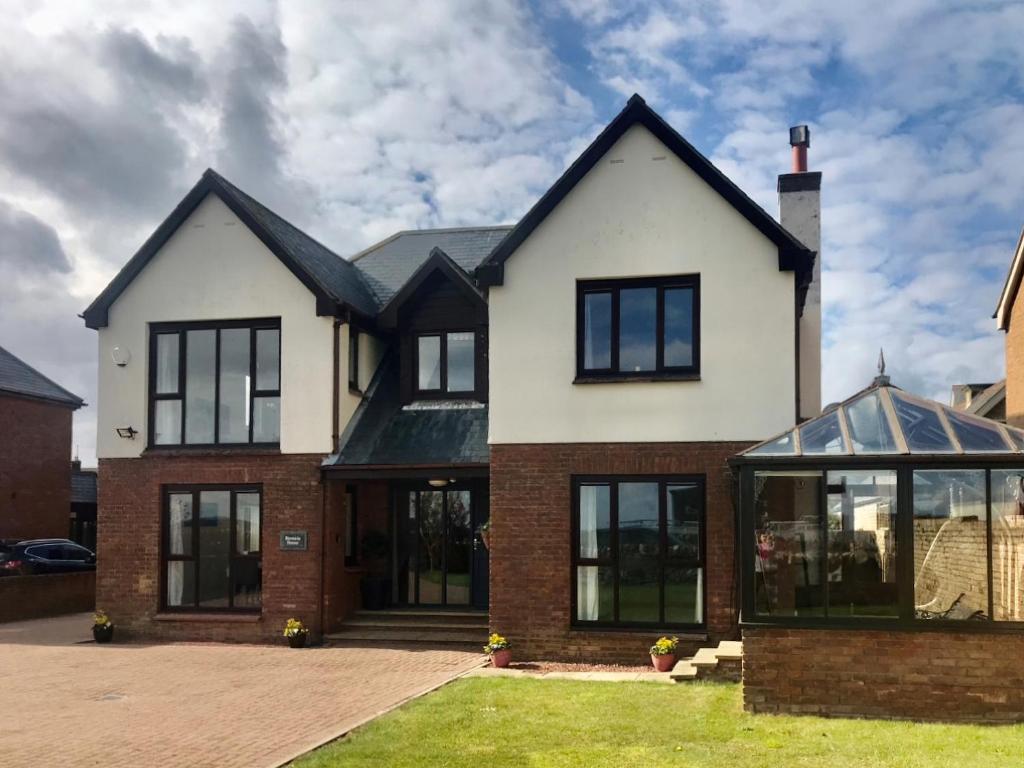 a large white house with black windows at Bernicia House in Seahouses