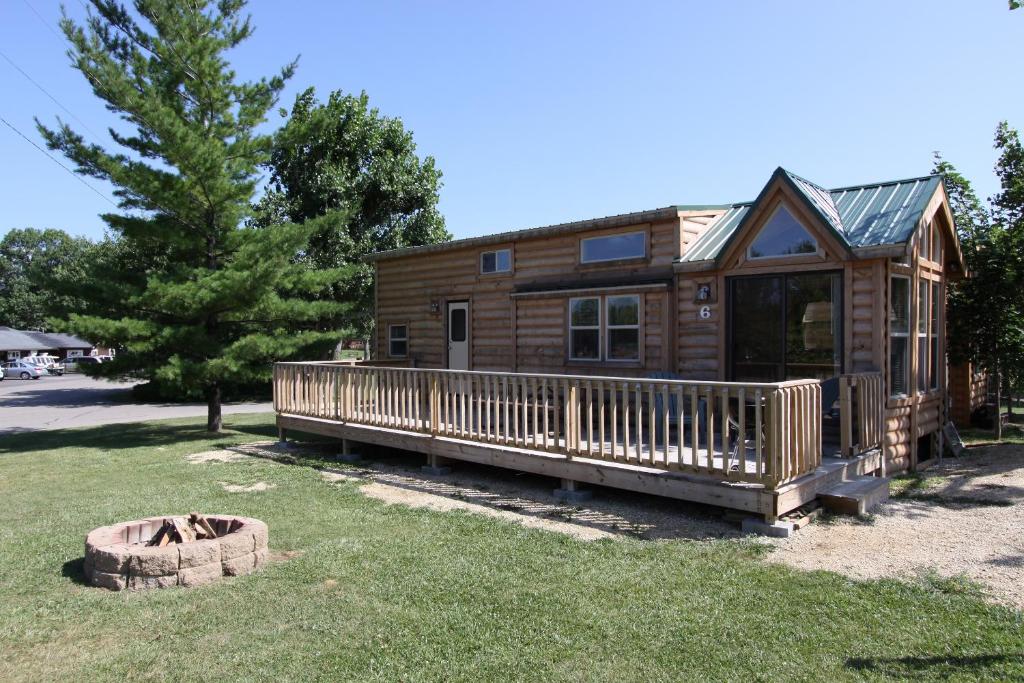 een blokhut met een grote veranda en een tuin bij Lakeland RV Campground Deluxe Loft Cabin 11 in Edgerton