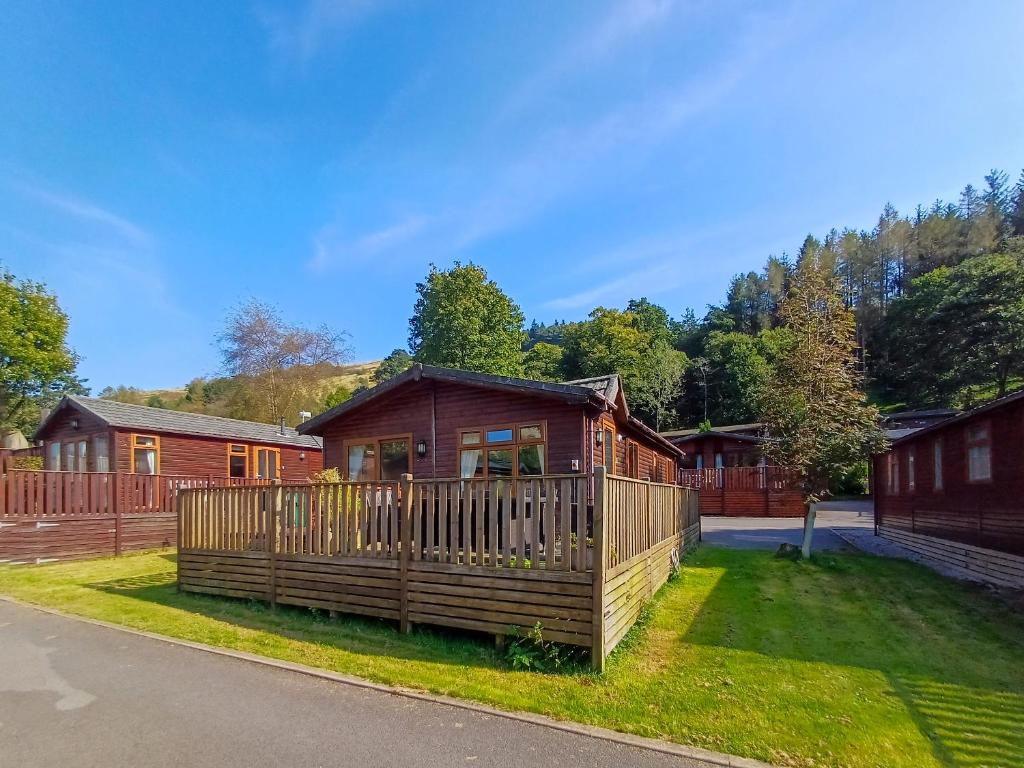 a wooden cabin with a fence in a yard at Bowness Lodge 12 Fellside in Windermere