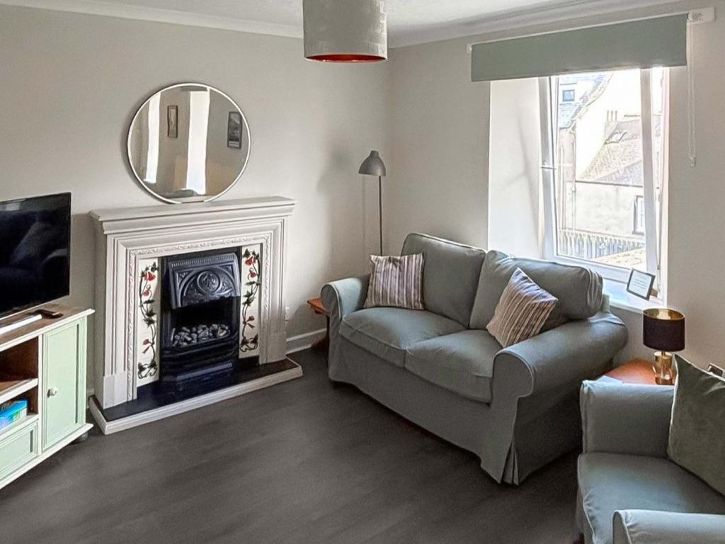 a living room with a couch and a mirror at India Lane Cottage in Montrose