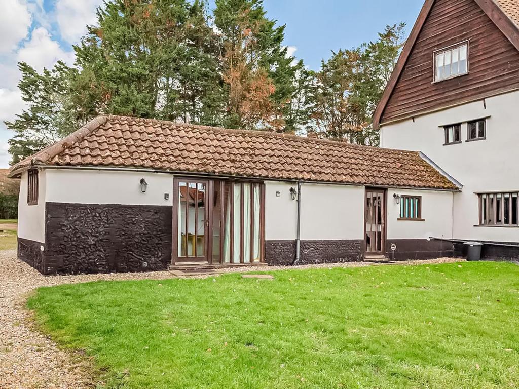 a white house with a grass yard in front of it at The Retreat - Uk48231 in Tibenham