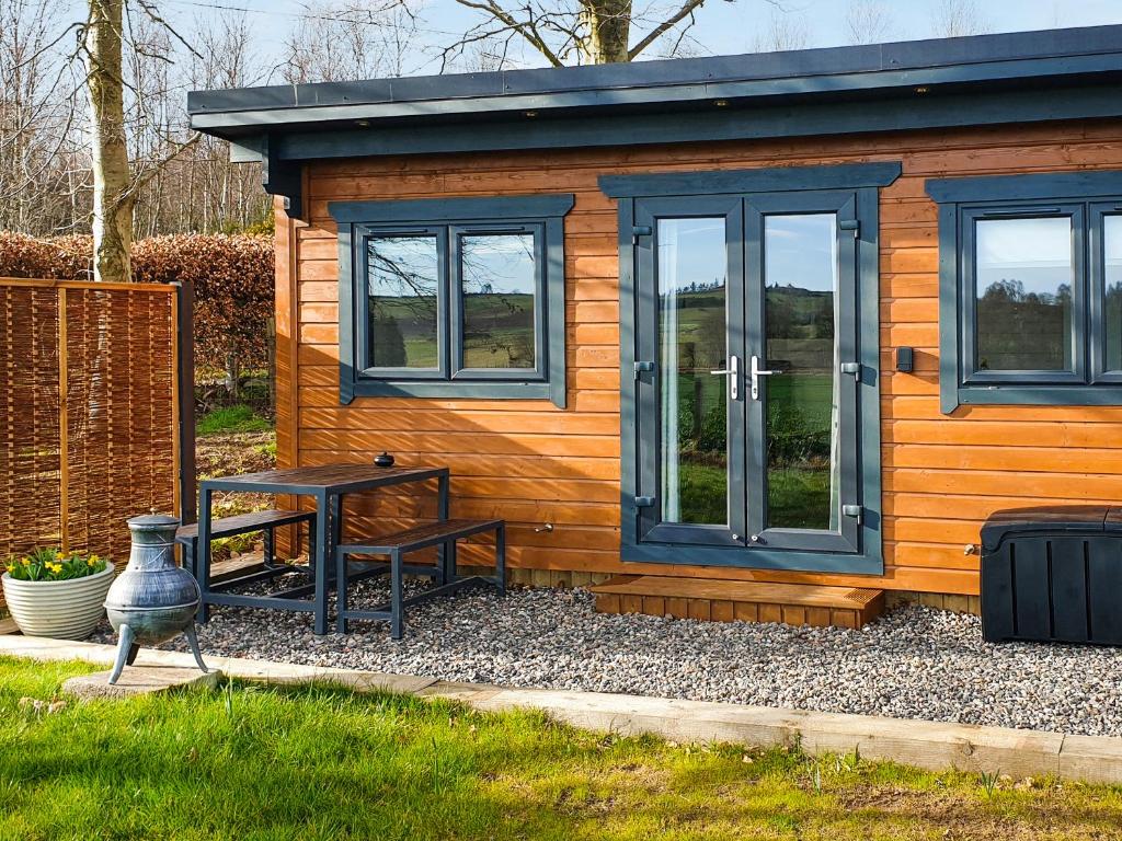 a small cabin with a table and a bench outside at Barn Owl Cabin - Uk45401 in Forfar