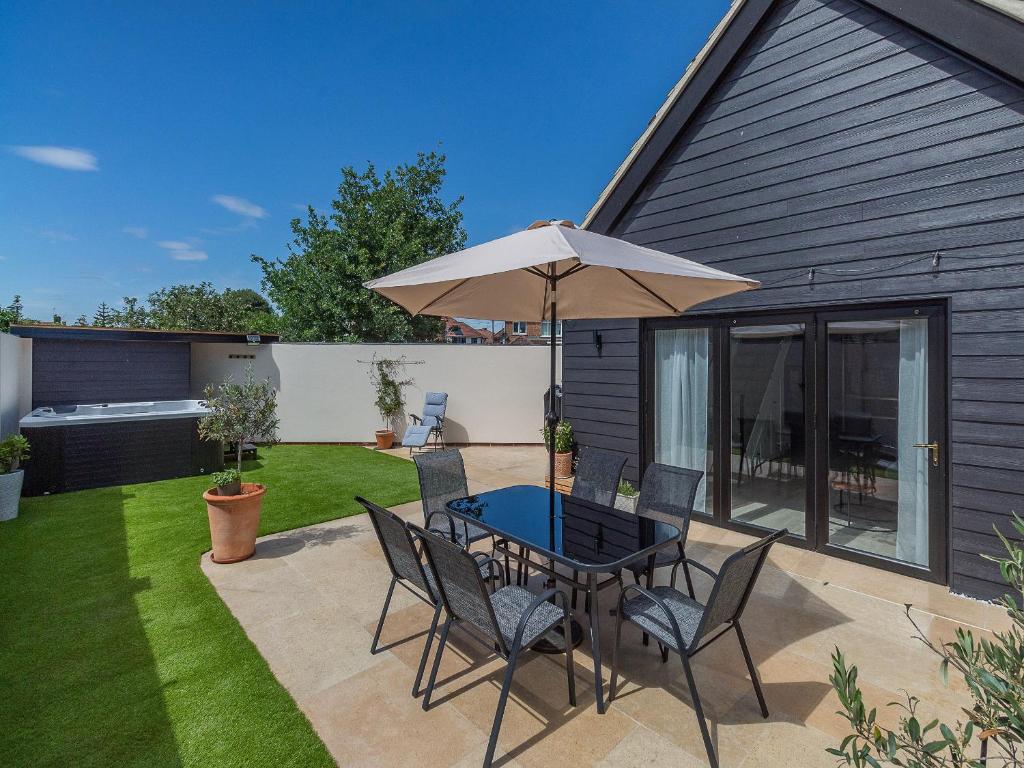 a patio with a table and chairs and an umbrella at Olive Breeze in Felixstowe