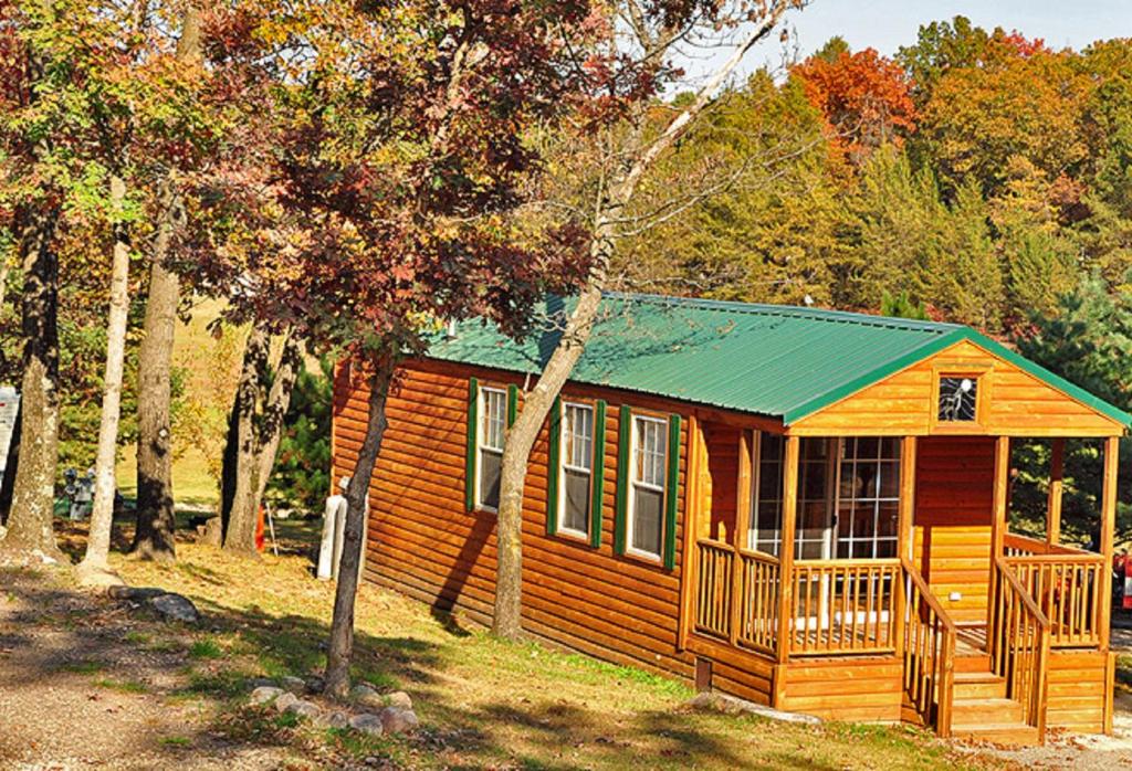 Cabaña de madera pequeña con techo verde en Arrowhead Camping Resort Deluxe Cabin 4 en Douglas Center