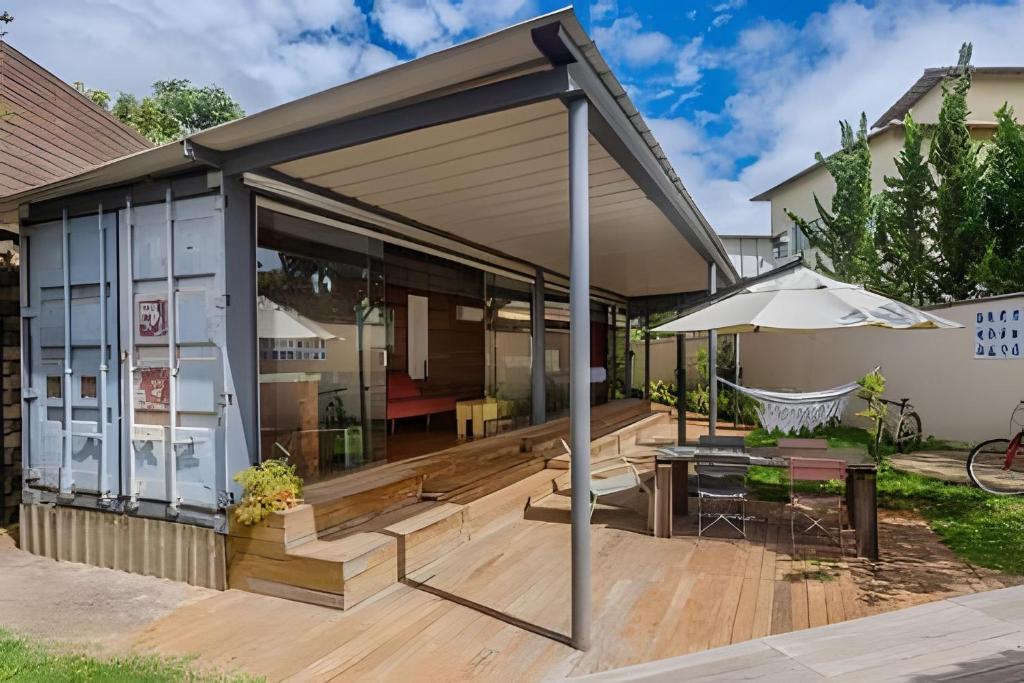 a house with a deck with a table and an umbrella at Casa Pantuso - Vale do Sol in Nova Lima