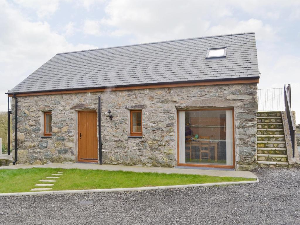a stone house with a door and a window at Rhiwal Kitty - Uk6000 in Bodedern