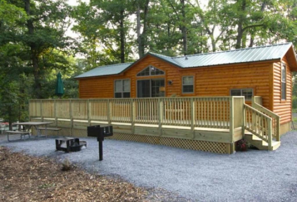 Cabaña de madera con terraza y mesa de picnic en Lakeland RV Campground Cottage 15, en Edgerton