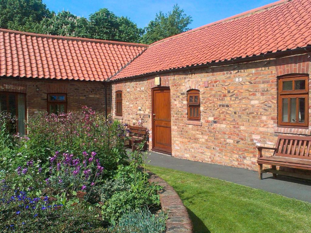 a brick building with a bench and a garden at Rievaulx Cottage in Filey