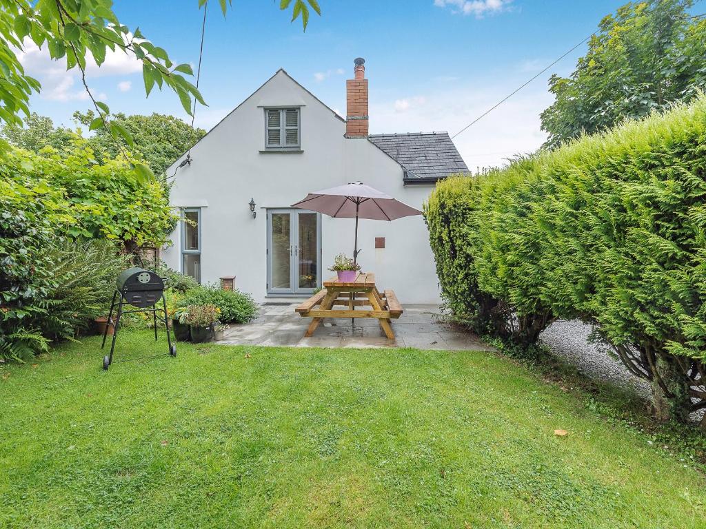 a picnic table with an umbrella in front of a house at Windsmoor Cottage On Gower in Penrice