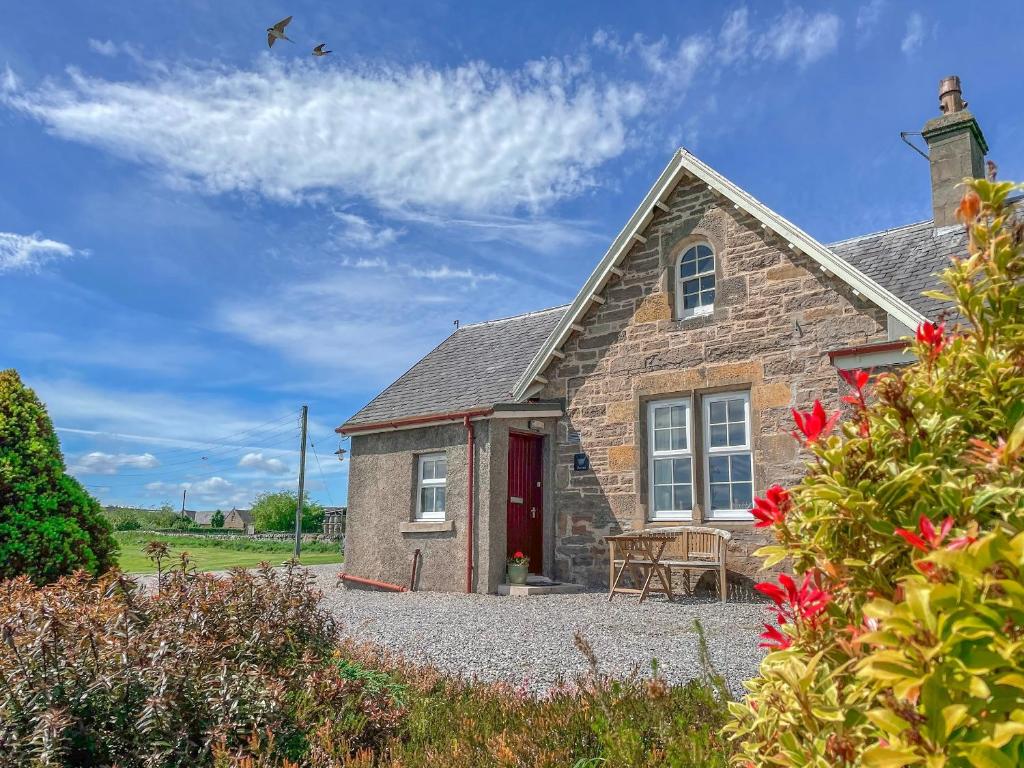 an old stone house with a red door and flowers at Rowan Cottage - Uk38991 in Dalcross