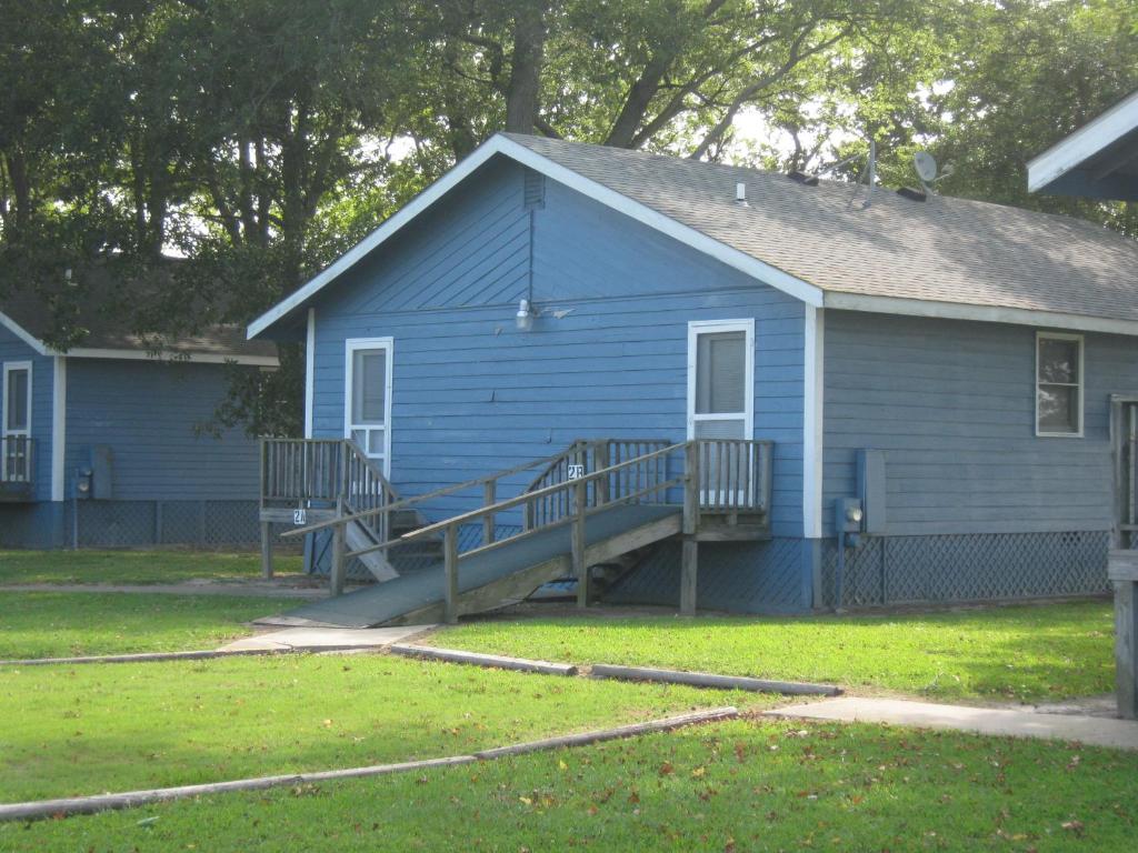 a blue house with a porch and a deck at Virginia Landing Camping Resort Cabin 1 in Quinby