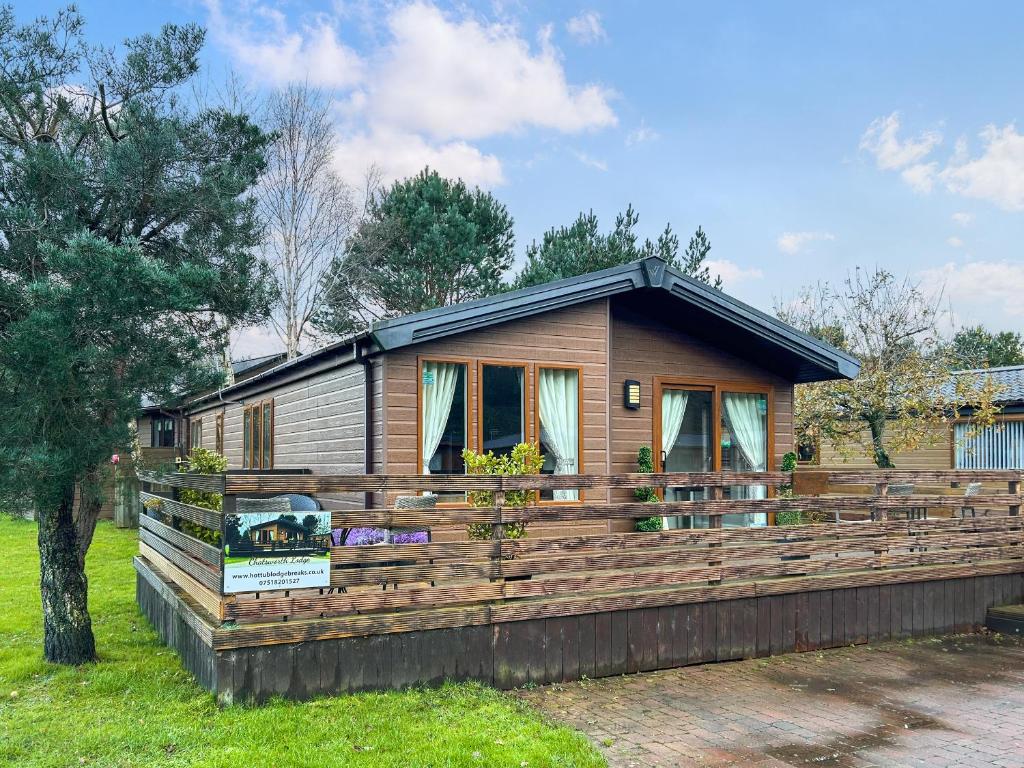 a small house with a large wooden deck at Chatsworth Lodge - Uk50983 in Felton