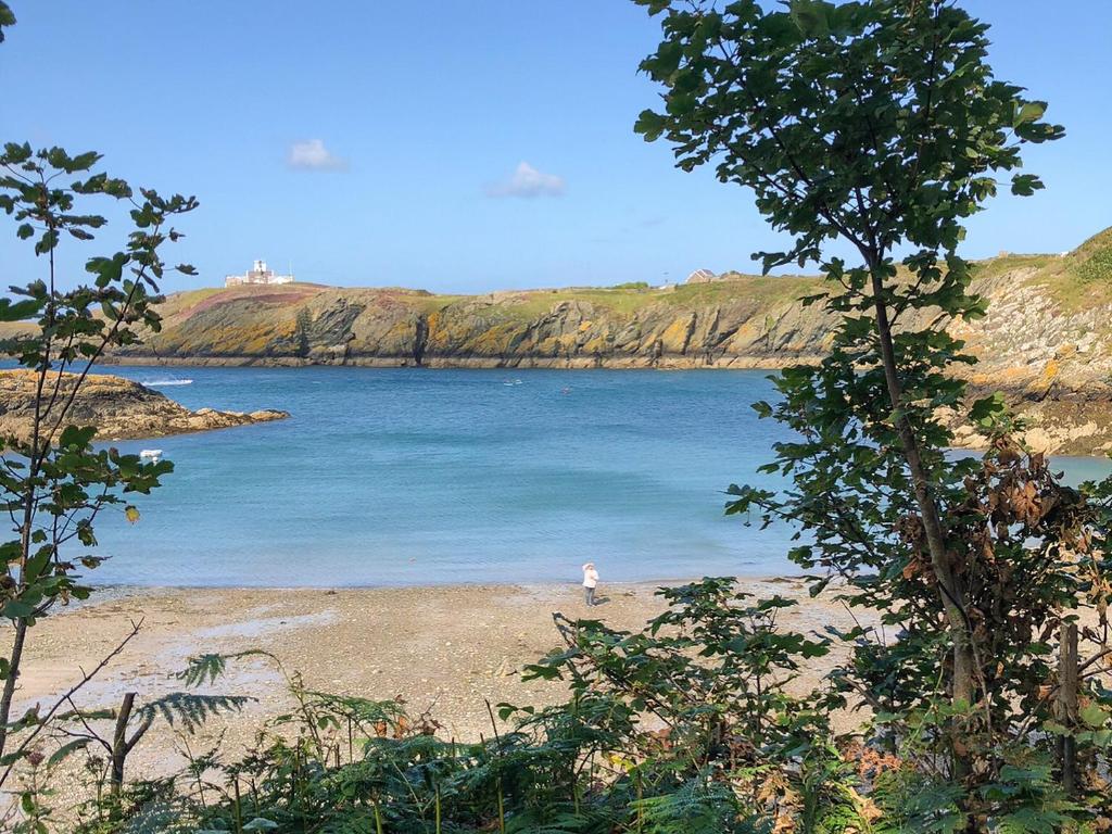 a person standing on a beach near the water at Copper Crab Cottage in Amlwch