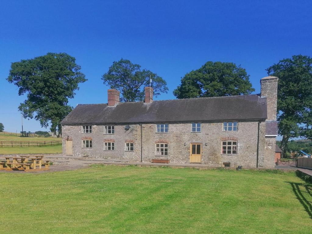 an old stone house with a large grass field at Colstey Farmhouse in Acton