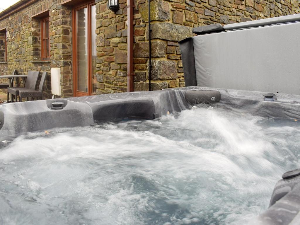 a jacuzzi tub with water in front of a building at Tan-Y-Derwwen in Mydroilin