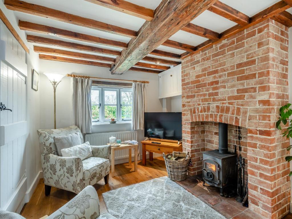a living room with a brick wall and a fireplace at Swallow Cottages, No 2 - Uk46810 in Thurgarton