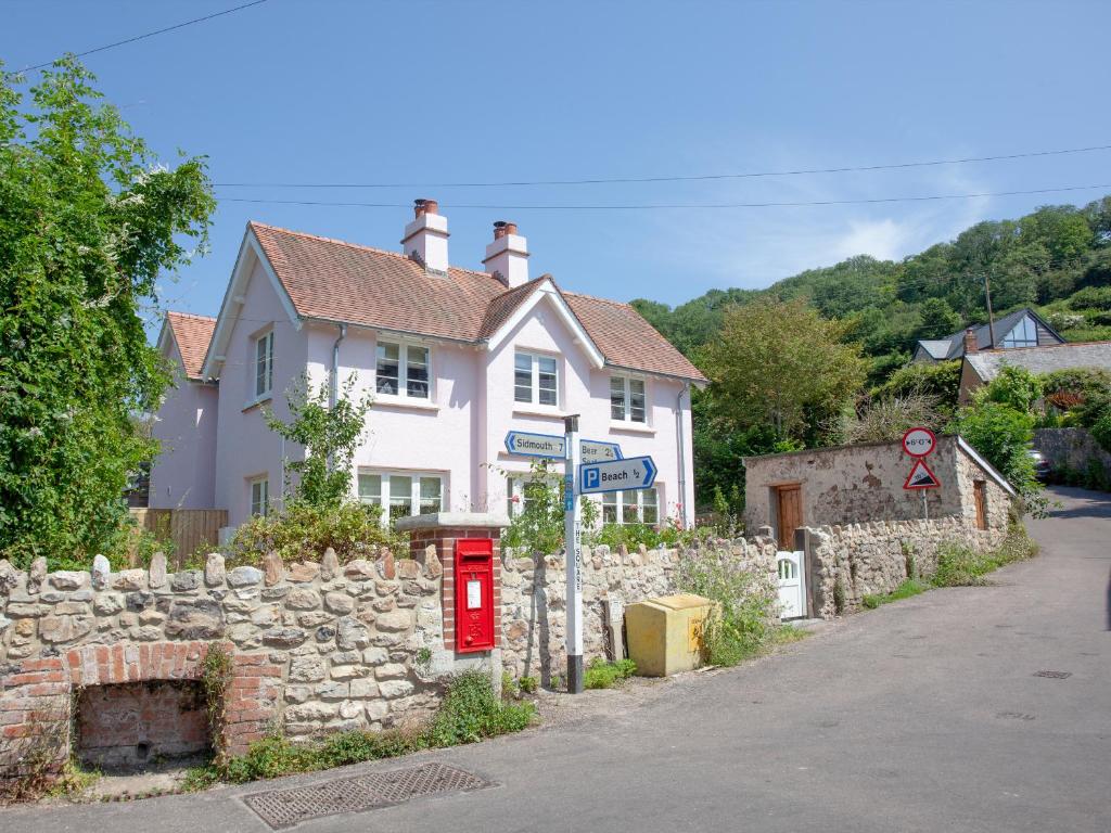 a white house with a stone wall and a red mailbox at The Pink House in Branscombe