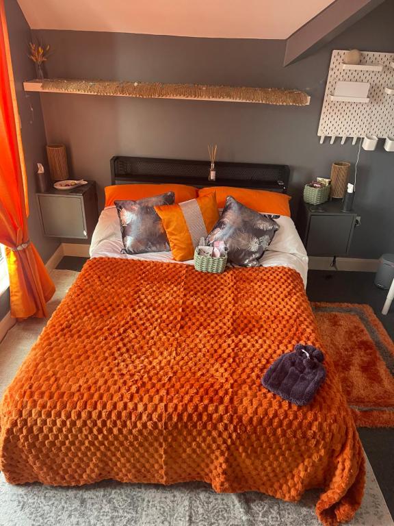 a bed with an orange comforter in a bedroom at Reggae Beach Getaway in Saltdean