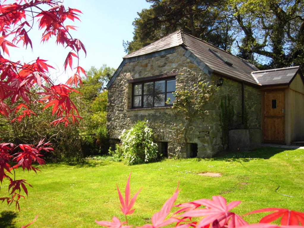 a small stone house in a yard with red leaves at Tamar Orchard Barn in Gunnislake