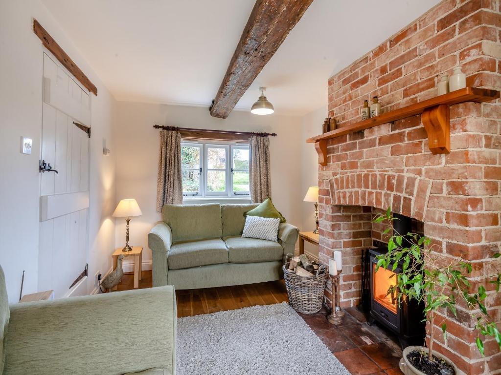 a living room with a brick fireplace and a couch at Swallow Cottages, No 1 - Uk46811 in Thurgarton