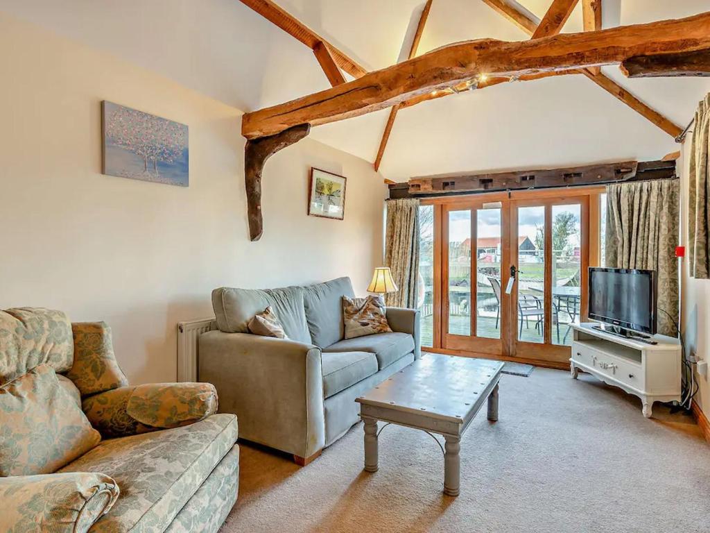 a living room with a couch and a tv at Pond View Cottage - Uk48230 in Tibenham