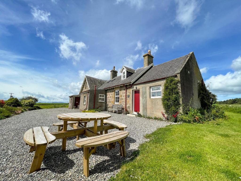 a house with picnic tables in front of it at Pine Cottage - Dalcross in Dalcross