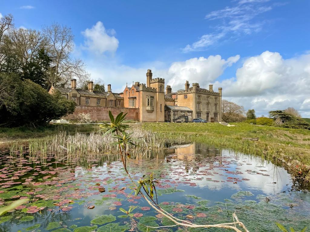 a castle with a pond in front of it at Apartment At Llanerchydol Hall in Welshpool