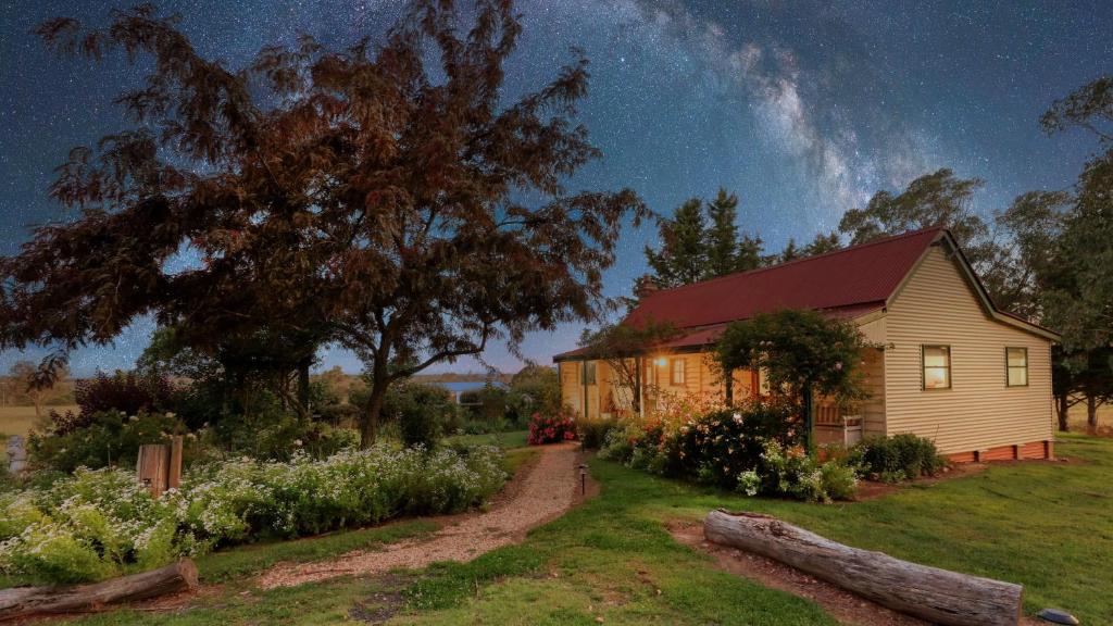 a house in a yard with a tree and flowers at Red Hill Cottage Walcha in Walcha