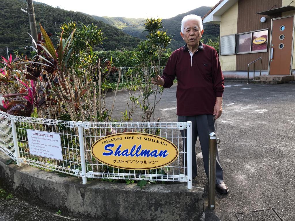 an older man standing in front of a sign at Guest in Shallman in Amami