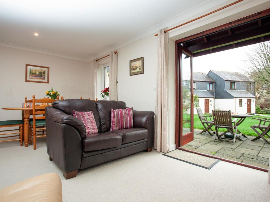 a living room with a leather couch and a sliding glass door at Gull Cottage in Falmouth