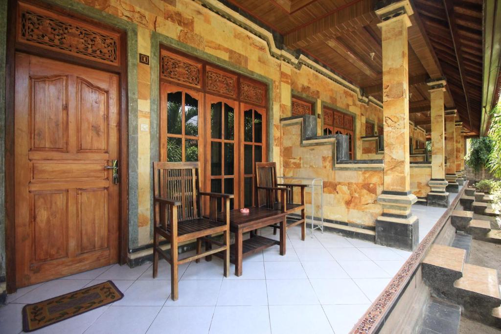 a house with a wooden door and chairs on a porch at Jepun Bali Bungalow in Nusa Lembongan